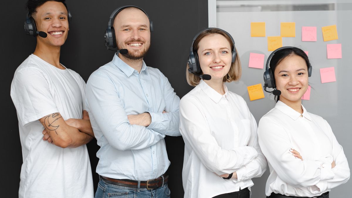 Práca v call centre – usmiaty mladý tím operátorov s headsetmi